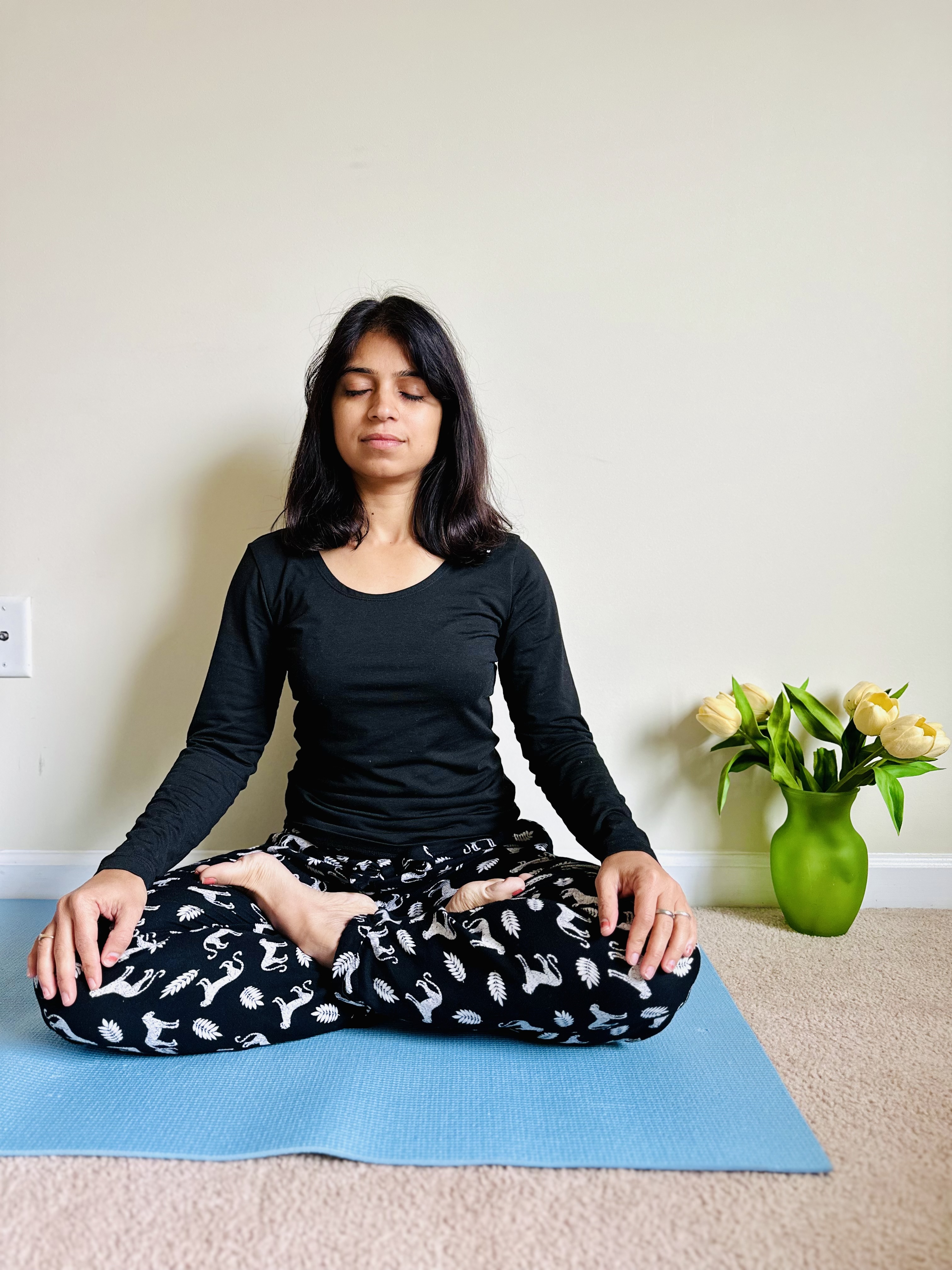 Latika leading a calm, gentle yoga pose on a mat in a bright living room